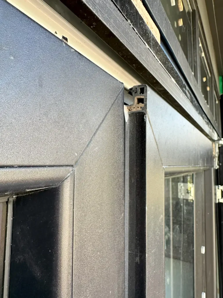 A door sash sitting 20mm proud of where it should be as a result of damaged hinges by the installers trying to fix mistakes made earlier in the installation process.